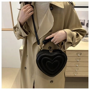 Close-up of black heart-shaped handbag with pleated handle and triple embossed texture