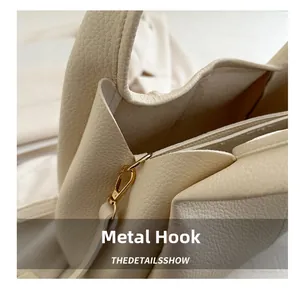 Detail eines hellgoldenen Hardware-Hakens und Leder mit Litschi-Maserung an beiger Tasche
