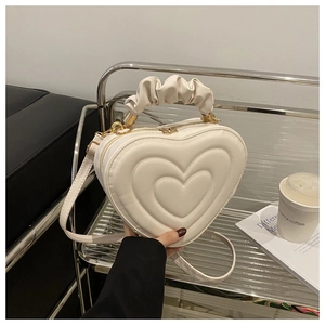 Detailed view of heart-shaped handbag featuring quilted textures and a ruffled handle