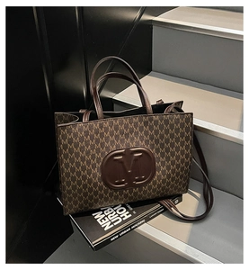 Détail du cabas en cuir marron foncé avec imprimé M et logo rond embossé élégant