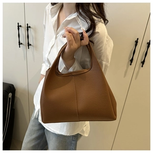 Detailansicht der karamellbraunen Eimer-Tasche aus Leder mit feiner Lychee-Narbung