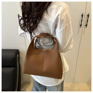 Braune Beuteltasche aus Leder mit Narbung, getragen von einem Modell im Innenraum