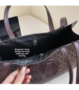 Detail view of the magnetic snap closure on a vintage brown tote bag with M patterns