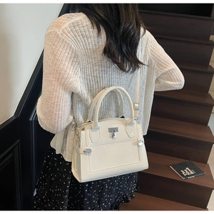 Litchi pattern ivory leather crossbody bag with metal buckle shown in a lifestyle setting