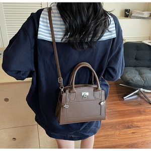 Brown litchi grain small square bag worn by a model in a cozy home interior setting
