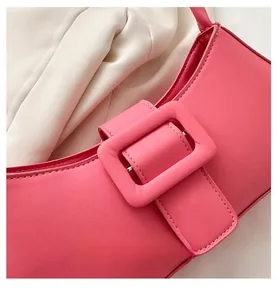 Détail d'un sac à bandoulière en cuir rose foncé avec une grande boucle carrée stylée