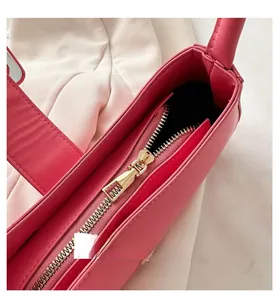 Gros plan sur la fermeture éclair dorée et les coutures d'un sac à bandoulière rose chic