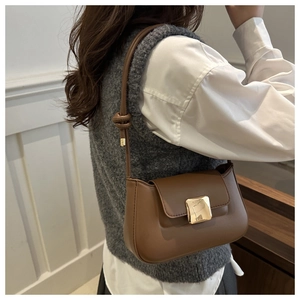 Detail view of a vintage brown leather shoulder bag with square golden buckle and knot strap