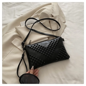 Detail of black crossbody bag featuring decorative rivets in a V-shaped texture