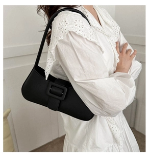 Détail d'un sac à bandoulière baguette en cuir noir avec une grande boucle carrée sur un modèle