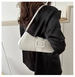 Gros plan du sac croissant blanc avec boucle carrée sur une veste de costume noire