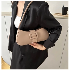 Gros plan d'un sac baguette beige minimaliste porté avec un blazer en satin noir