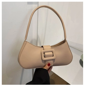 Détail du sac sous le bras beige montrant la texture du cuir mat et la boucle carrée