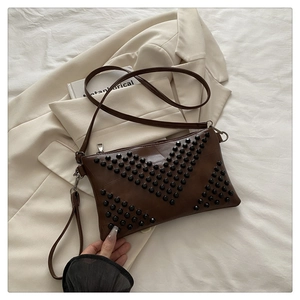 Detail of a brown envelope clutch bag featuring black rivets in a V-shape design