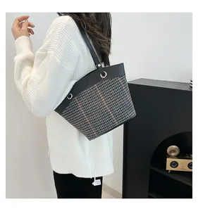 Detail of vintage houndstooth tote bag with leather straps on a minimalist background