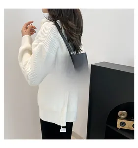 Detail of houndstooth tote bag with black leather trim worn by model in minimalist setting