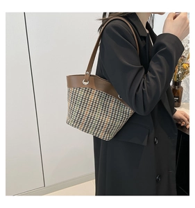Detail showing retro houndstooth pattern fabric and brown leather strap on a shoulder bag