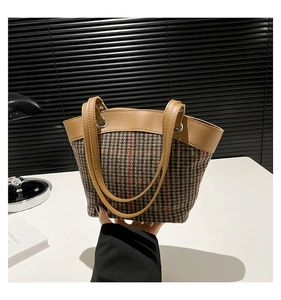Detail of vintage houndstooth tote bag featuring brown faux leather trim and silver metal rings