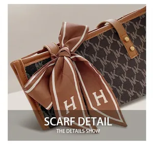 Close-up of large tote bag with NK pattern, brown leather trim and silk scarf detail