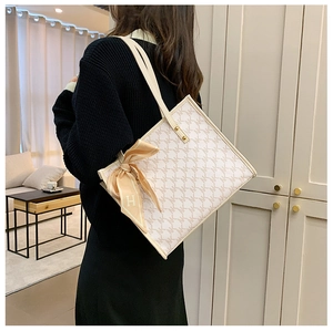 Detail of monogram tote bag with leather straps and decorative scarf on a shoulder