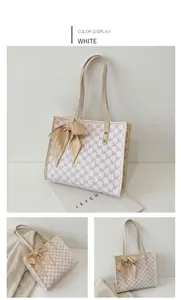 Close-up of cream tote bag with NK monogram and decorative silk scarf detail