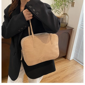 Detail of minimalist beige faux suede shoulder bag with sleek silver zipper closure