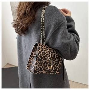 Detail of leopard print crossbody bag featuring a gold chain strap and metal lock closure