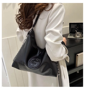 Detail einer schwarzen Hobo-Tasche aus Leder mit Logo-Prägung und Metallkettenriemen