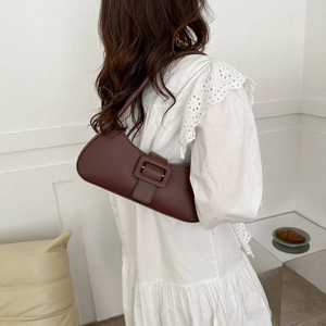 Sac à bandoulière en cuir marron avec boucle carrée porté sur une robe blanche