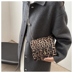 Detail view of leopard print crossbody bag with gold chain strap and metal lock closure