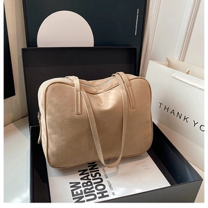Detail of a beige suede tote bag with metal zipper placed in a premium gift box