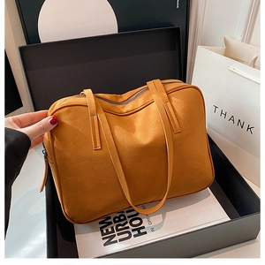 Detail of a ginger yellow suede tote bag inside a gift box with a vintage square design