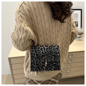 Leopard print crossbody bag with gold chain strap shown in a cozy lifestyle setting