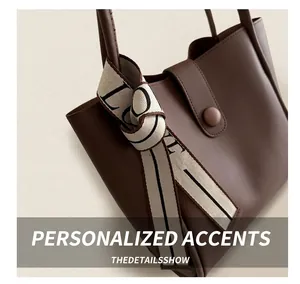 Detailed view of brown leather tote bag with a decorative LOVE ribbon handle detail