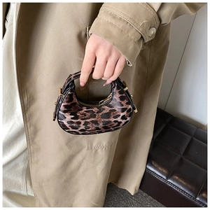 Close-up of leopard print crescent bag with golden zippers and adjustable buckle