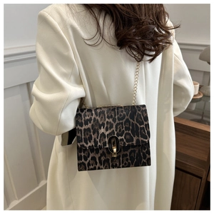 Detail of leopard print crossbody bag with gold chain strap on a white blazer