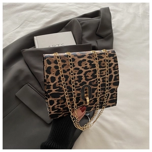 Close-up of leopard print crossbody bag featuring a gold chain and oval metal clasp
