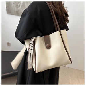 Detail of cream leather tote bag with brown trim and LOVE letter ribbon strap
