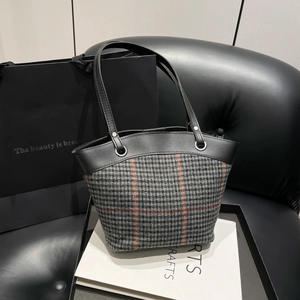 Vintage orange plaid bucket tote bag with leather strap on a stylish gift bag display