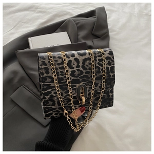 Detail of leopard print crossbody bag with gold chain and oval metal clasp on a blazer