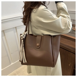 Detail of a large brown tote bag showing smooth leather texture and decorative silk scarf