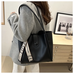 Detail of black faux leather tote bag with LOVE letter strap and circular metal clasp