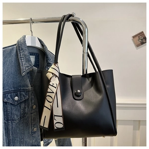 Detail of matte black tote bag featuring LOVE scarf and protective metal base studs