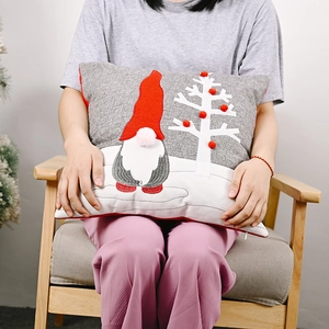 Detail of Christmas gnome pillowcase with red pom-poms on grey and white linen fabric