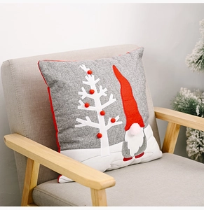 Detail of Christmas gnome and tree embroidery with red pom-poms on a grey cushion cover