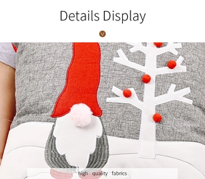 Detailed close-up of grey linen pillowcase with gnome embroidery and red pom-poms