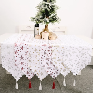 Détail d'un chemin de table de Noël avec marquage doré, tissu blanc et bords à franges
