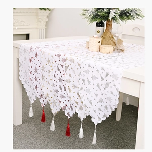 Détail du chemin de table de Noël blanc avec motifs dorés et glands élégants