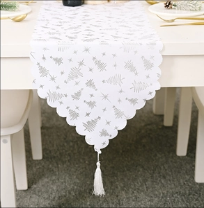 Détail du chemin de table de Noël blanc avec sapins argentés et pompons blancs