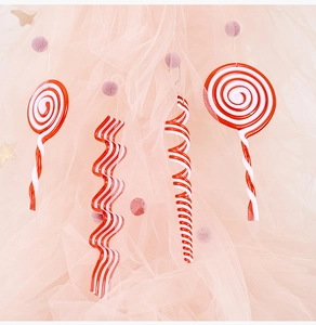 Detail of red and white candy Christmas ornaments on a soft pink dreamy fabric background